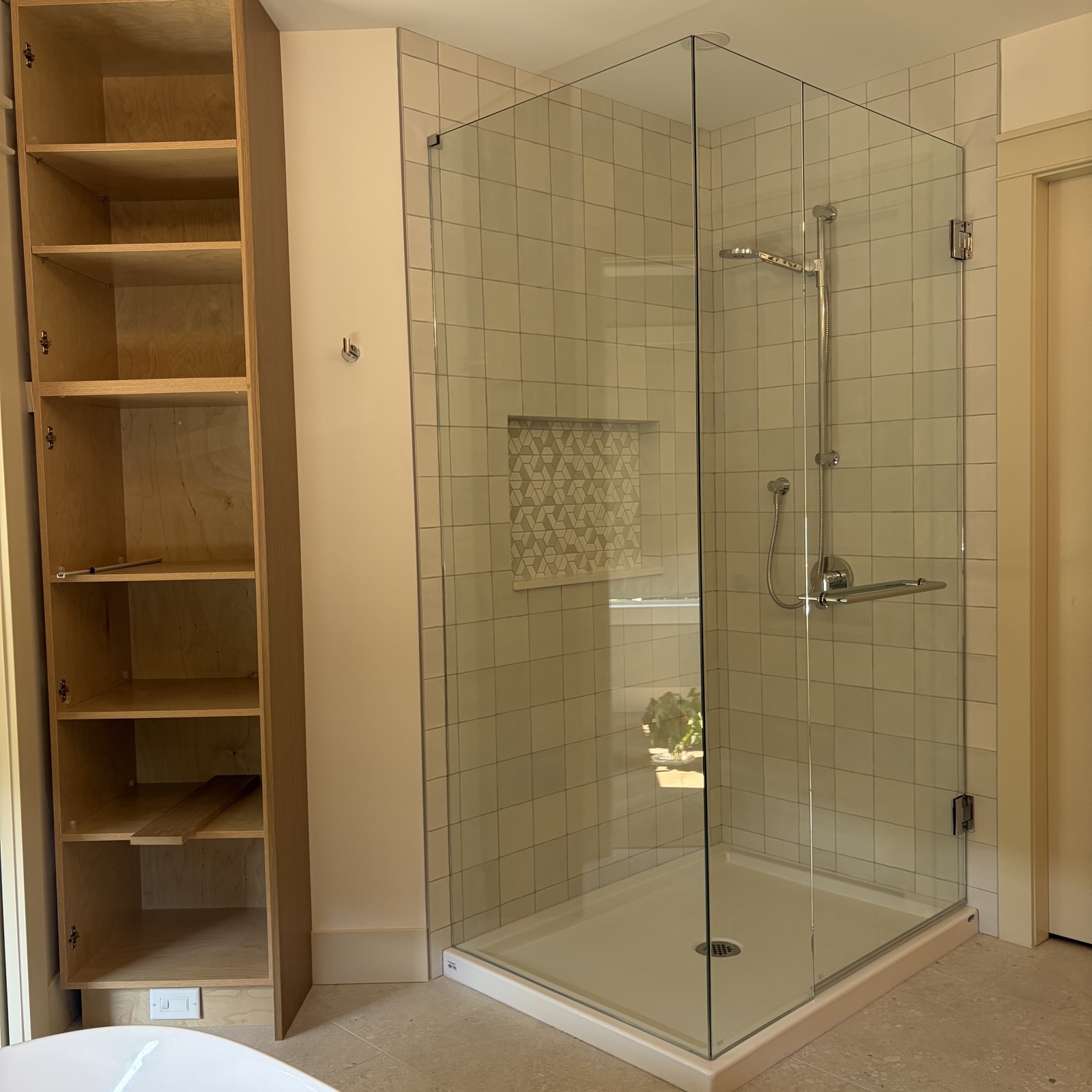 Frameless corner shower enclosure on square white tile, Kelowna