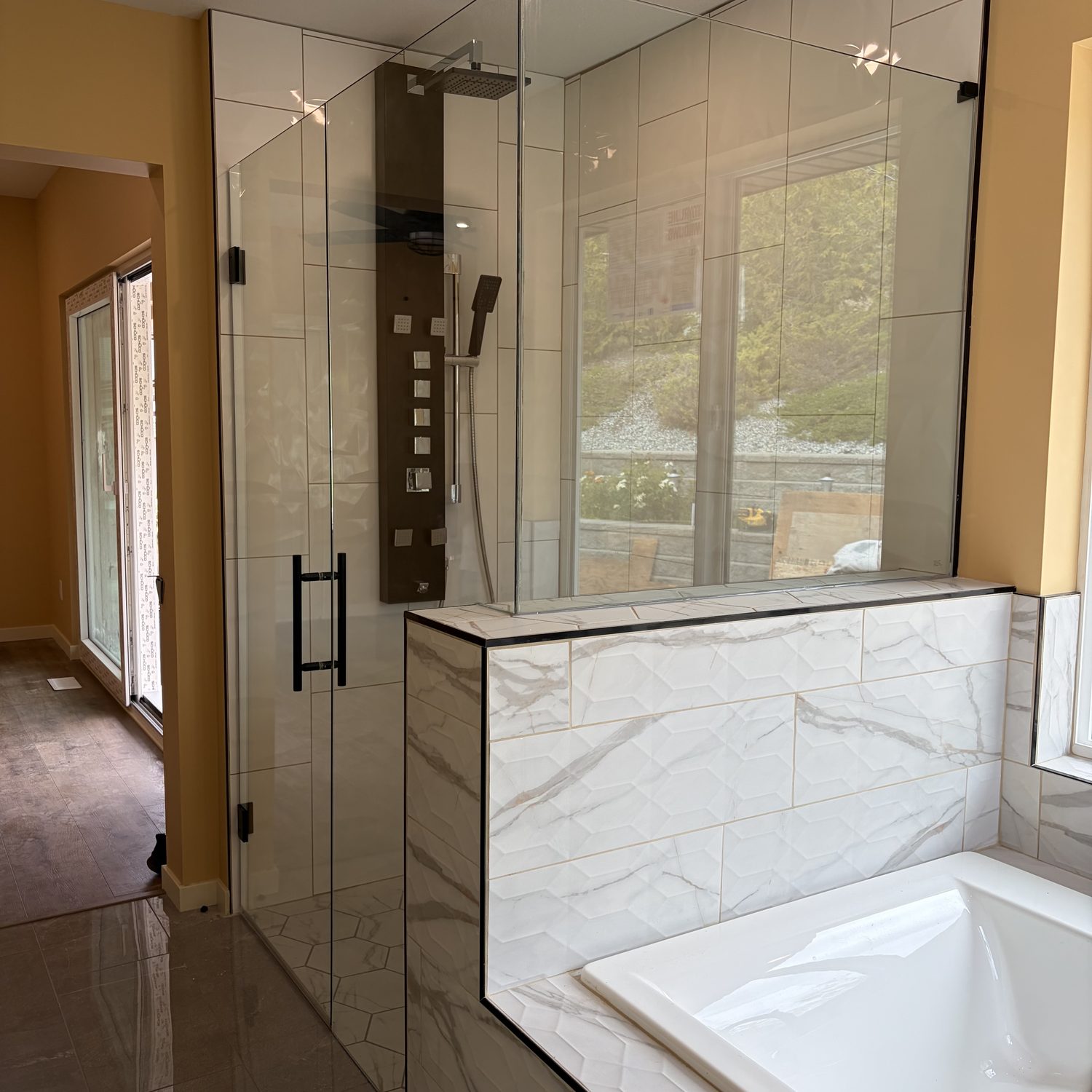 Frameless glass shower with marble tile and a lake view